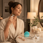 Woman in a robe using a skincare tool in a bathroom setting with various skincare products on a counter.
