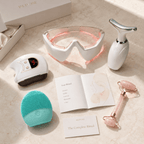 Set of skincare devices and tools on a marble surface.