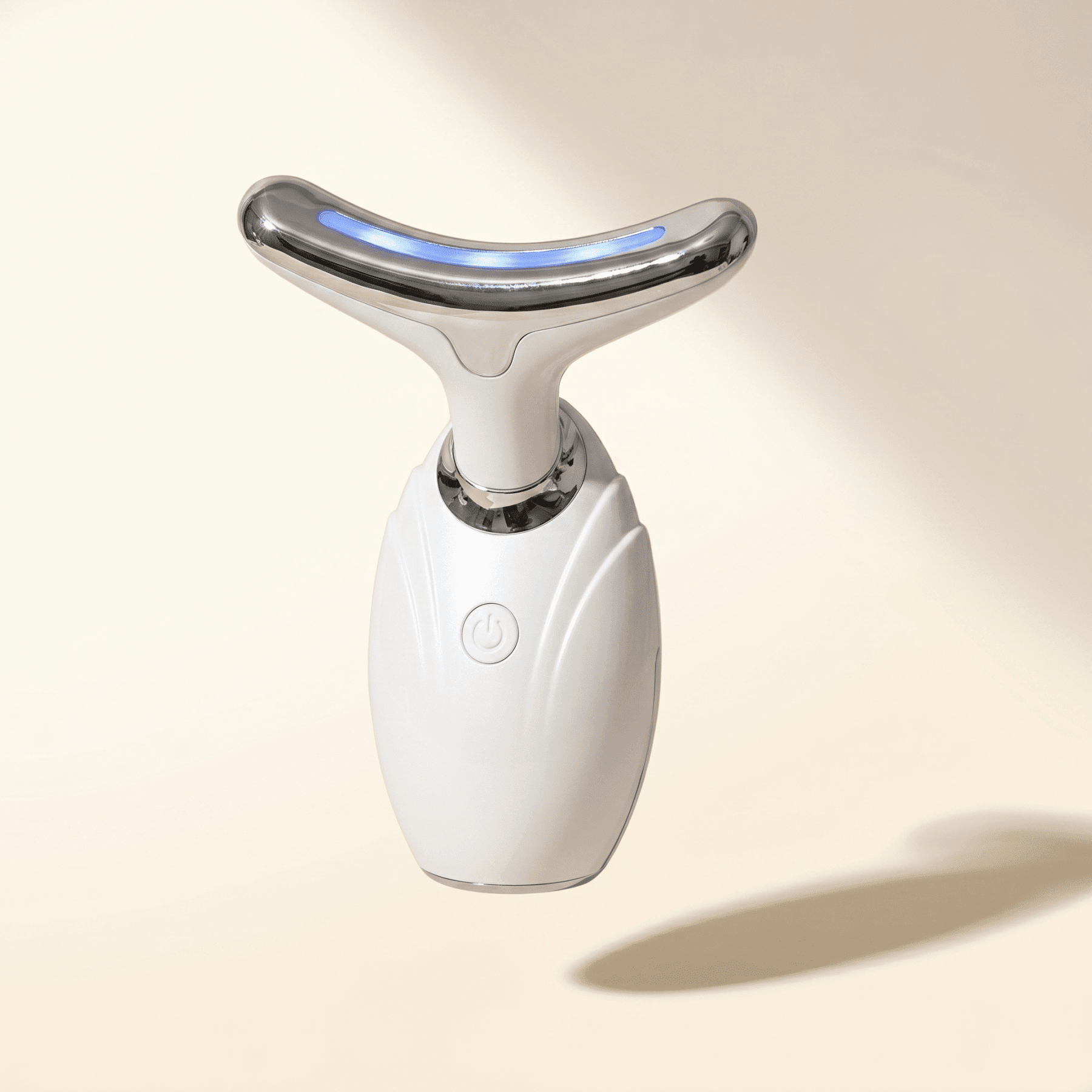 White facial conotour wand with a silver top on a beige background