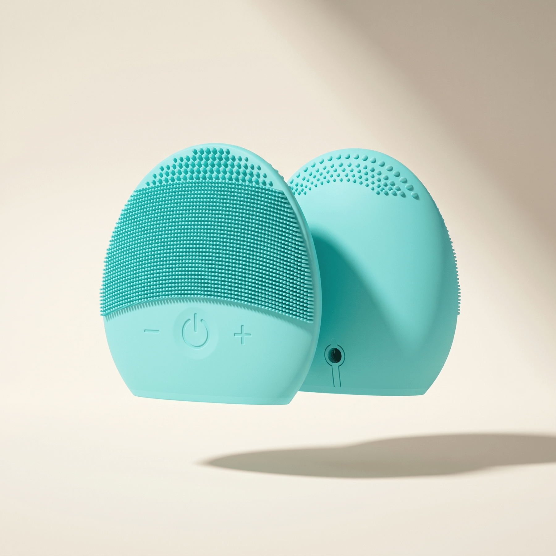 Turquoise silicone face cleansing brush on a beige background