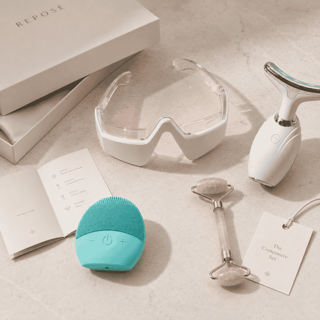 Collection of skincare and wellness tools including a teal device, goggles, and roller on a neutral background.