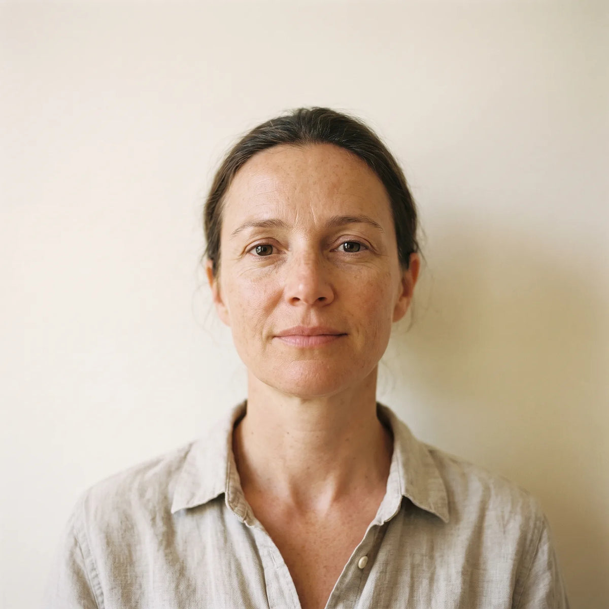 A woman in her forties looking straight at the camera in daylight, wearing no makeup.